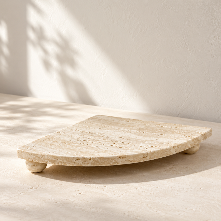 Footed Travertine Fan Tray on a cream stone surface in soft daylight